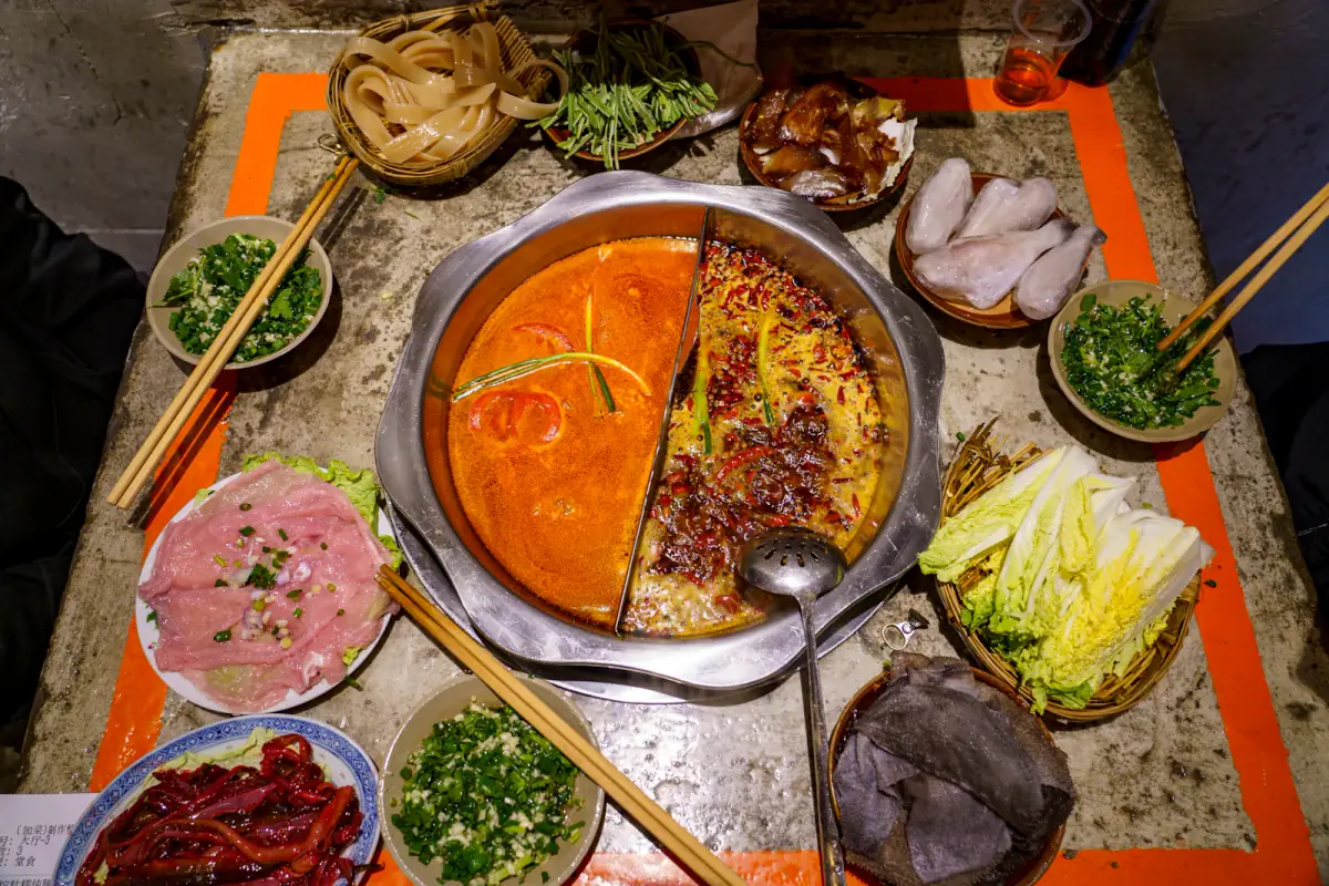 A shared table centered on bubbling red Sichuan-style hot pot