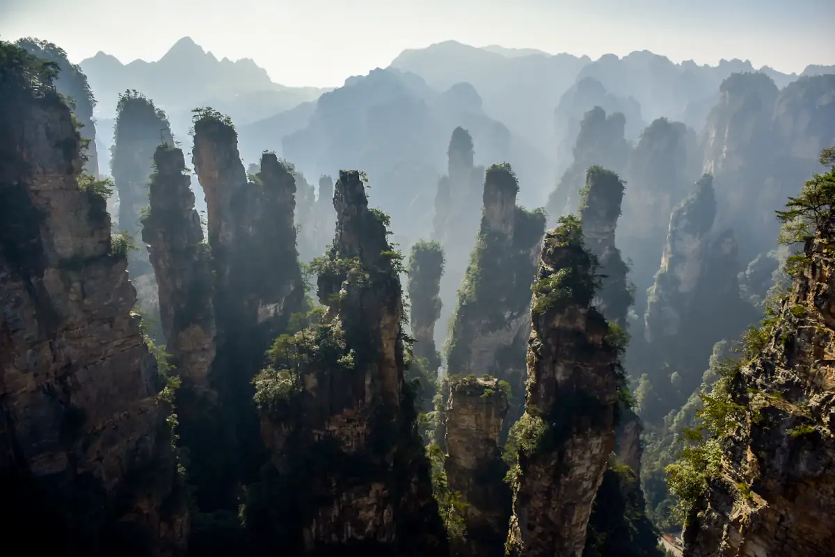 Tall sandstone pillars emerging through mist in Zhangjiajie